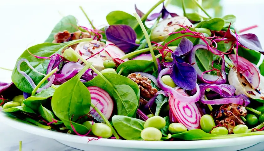 En färgglad sallad med spenat, rödlök, edamamebönor och valnötter. Perfekt som en lätt lunch, och ja, man kan värma spenat till den!