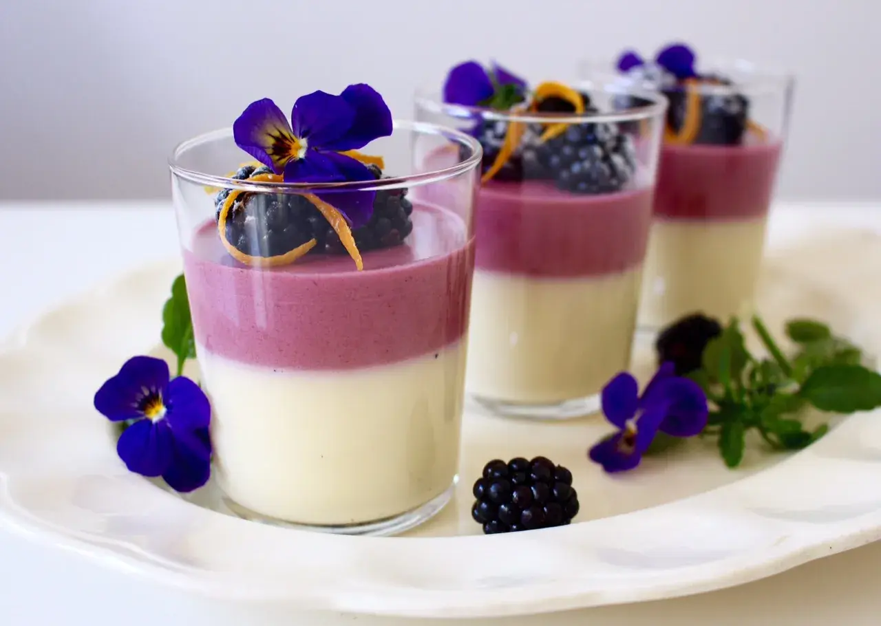 Tvåfärgade panna cotta med björnbär, apelsinzest och violer. En elegant dessert.
