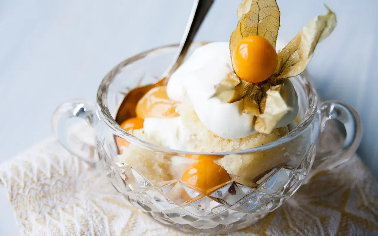 En härlig lemoncurd tårta i en kristallskål, toppad med grädde och physalis. En dröm för alla sötsugna!