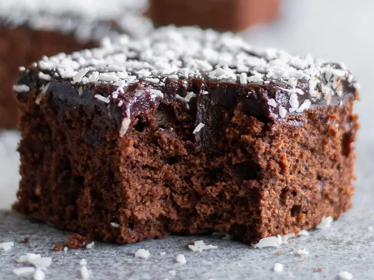 Saftig chokladkaka recept: en bit mörk chokladkaka med chokladglasyr och kokosflingor.