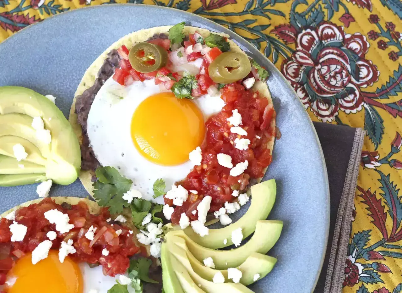 Två huevos rancheros med stekt ägg, svarta bönor, salsa, jalapeños och avokado. En härlig frukost!