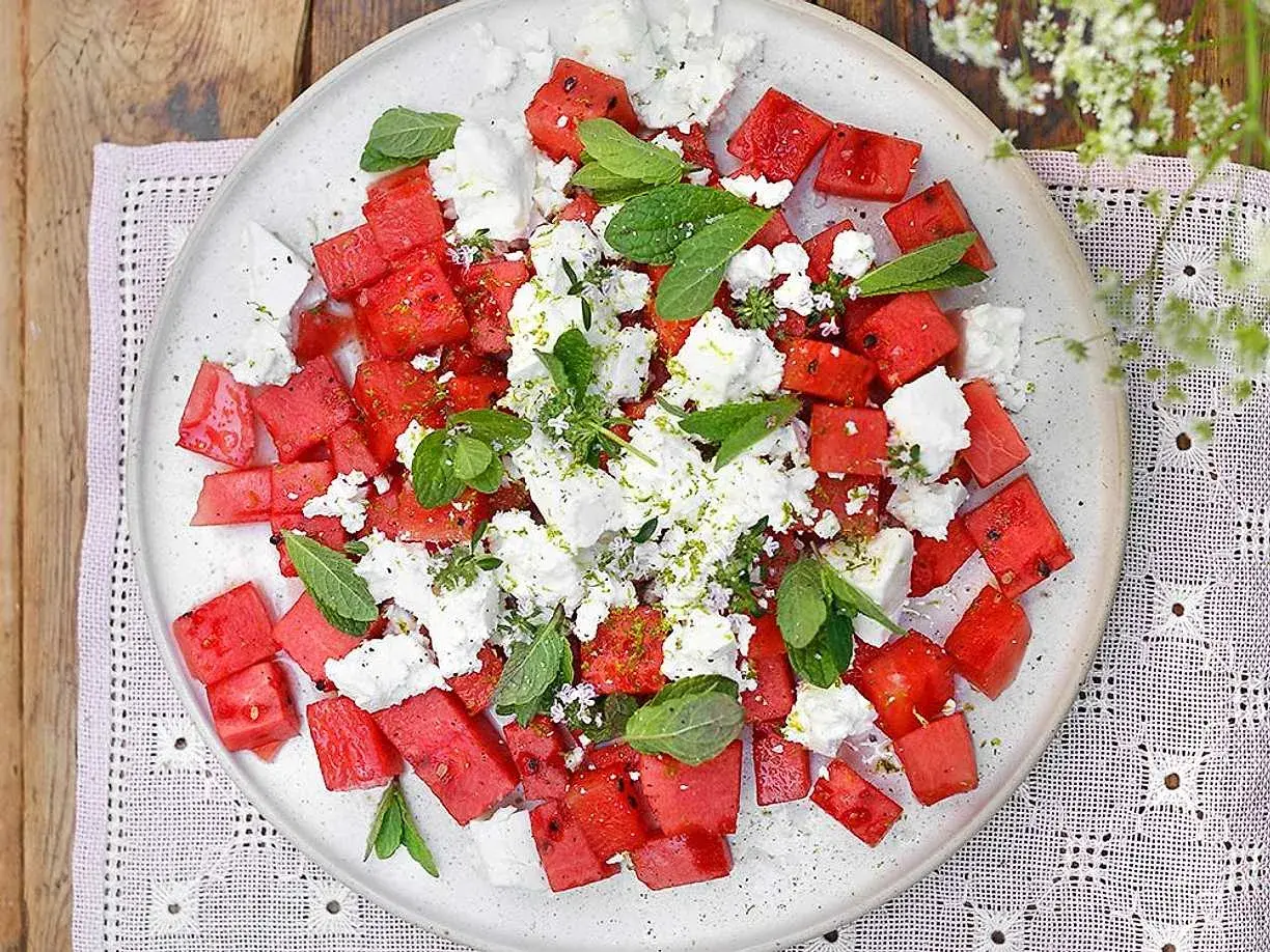 Watermelon and feta salad with mint and lime zest on a white plate.