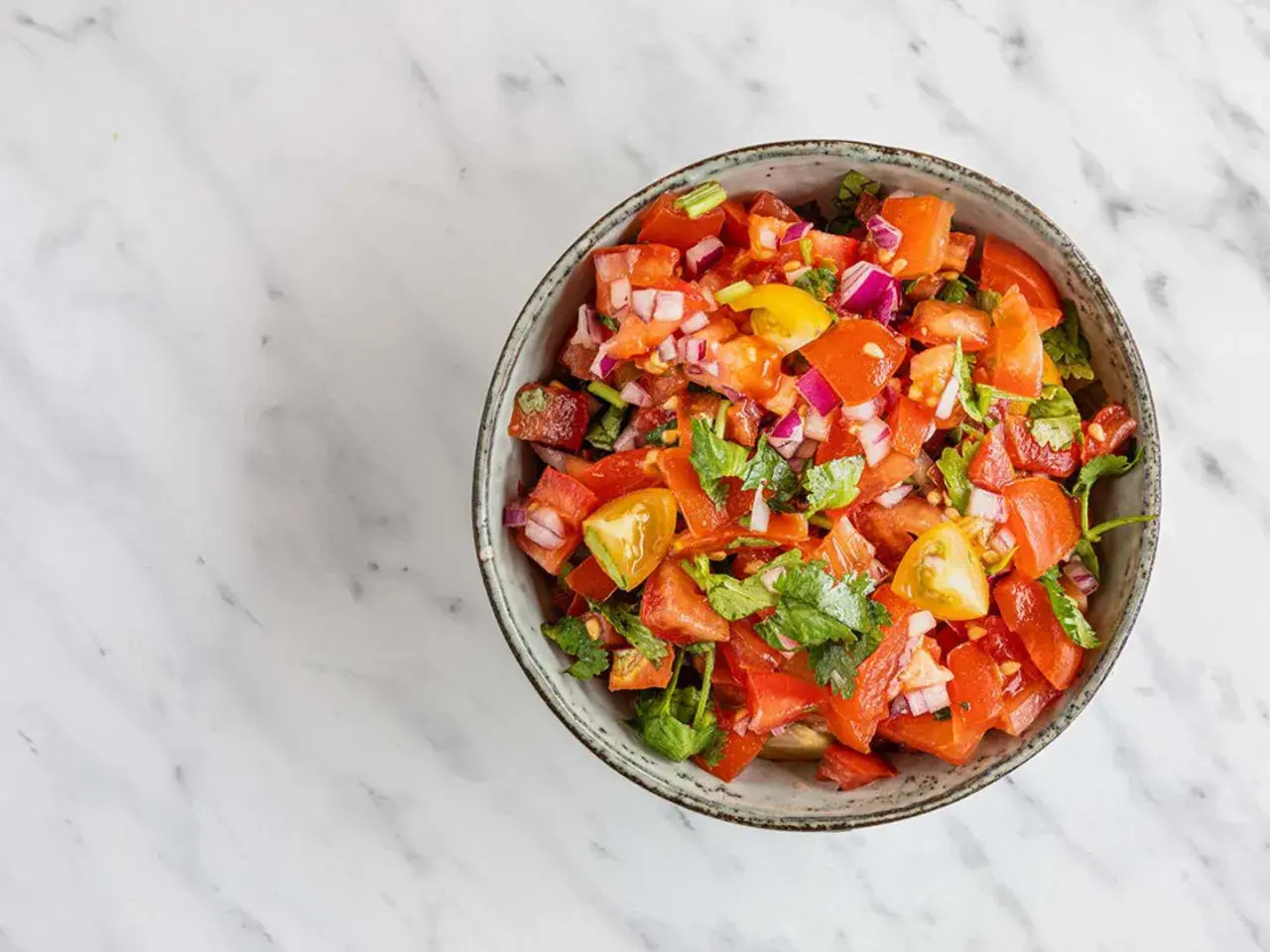 En skål med färsk pico de gallo, full av hackade tomater, rödlök och koriander, redo att serveras.