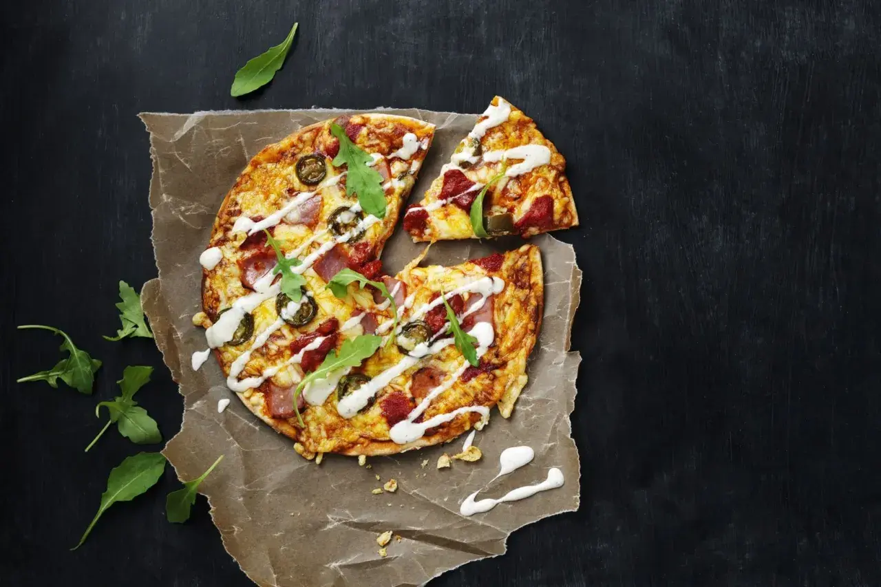 En läcker tortilla pizza med jalapeños, skinka och ruccola, ringlad med vit sås.