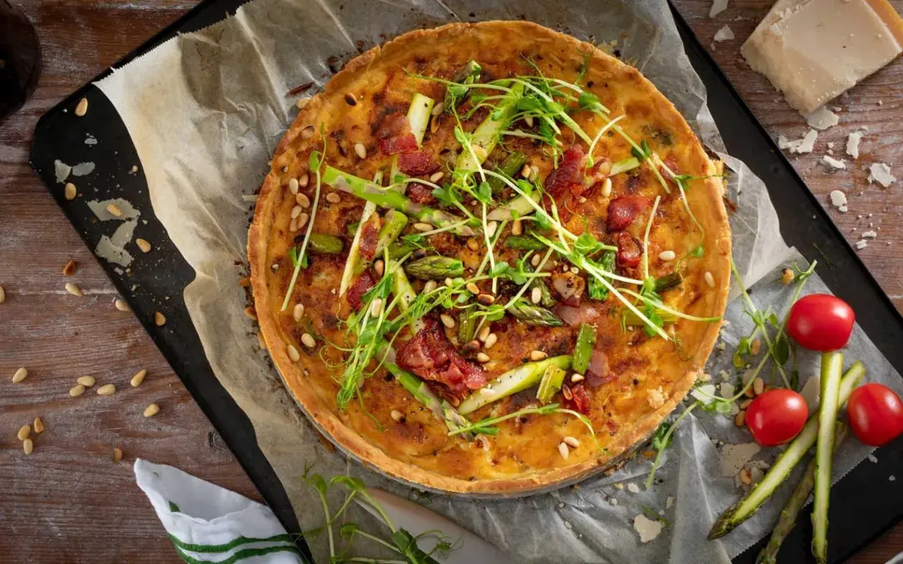 En gyllene sparrispaj med knaprigt bacon, pinjenötter och färska gröna toppar. Perfekt för en vårmåltid.