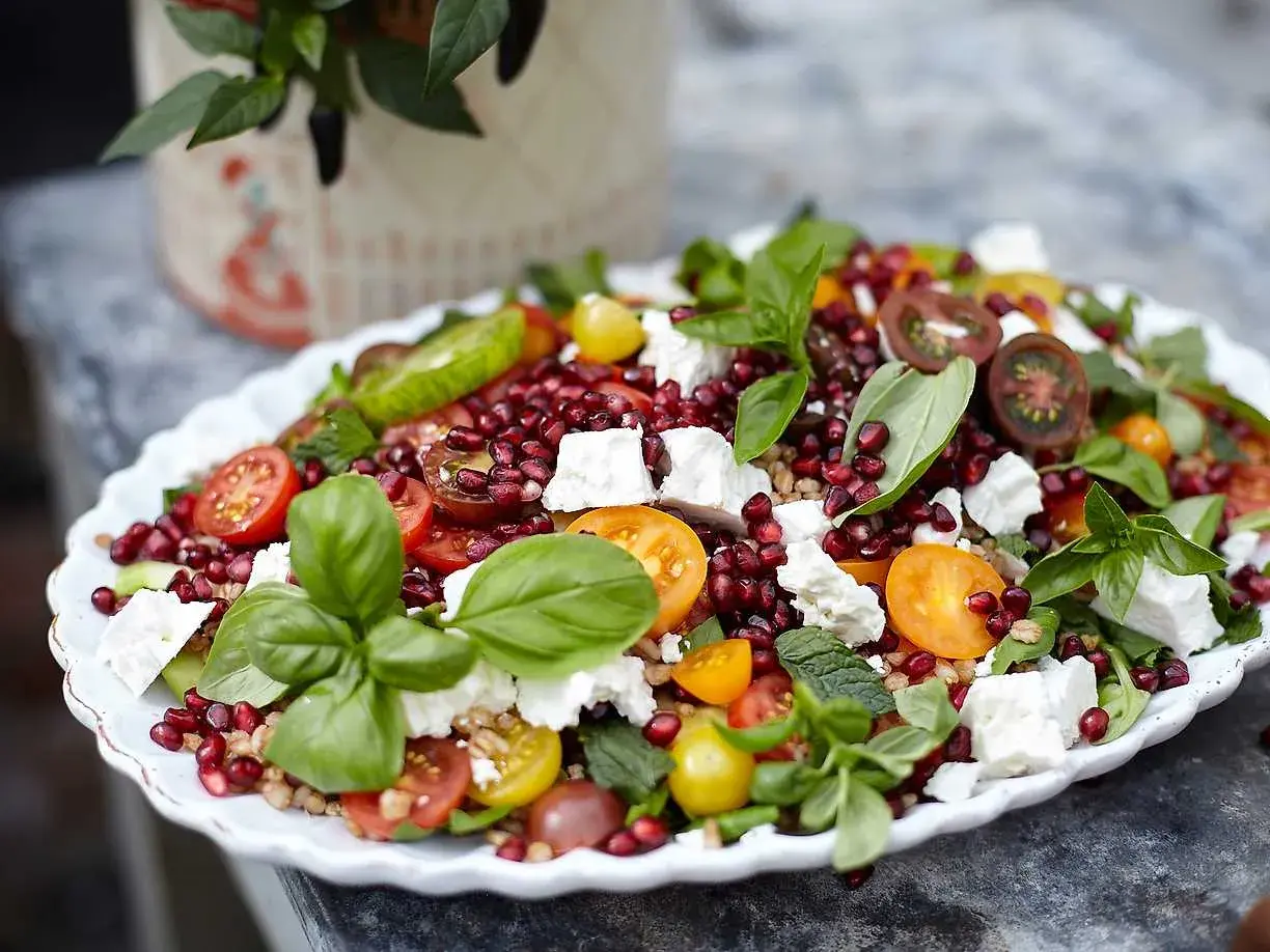 En härlig sallad med granatäpple, tomater, fetaost och färska örter. En riktigt god sallad som ser aptitlig ut.