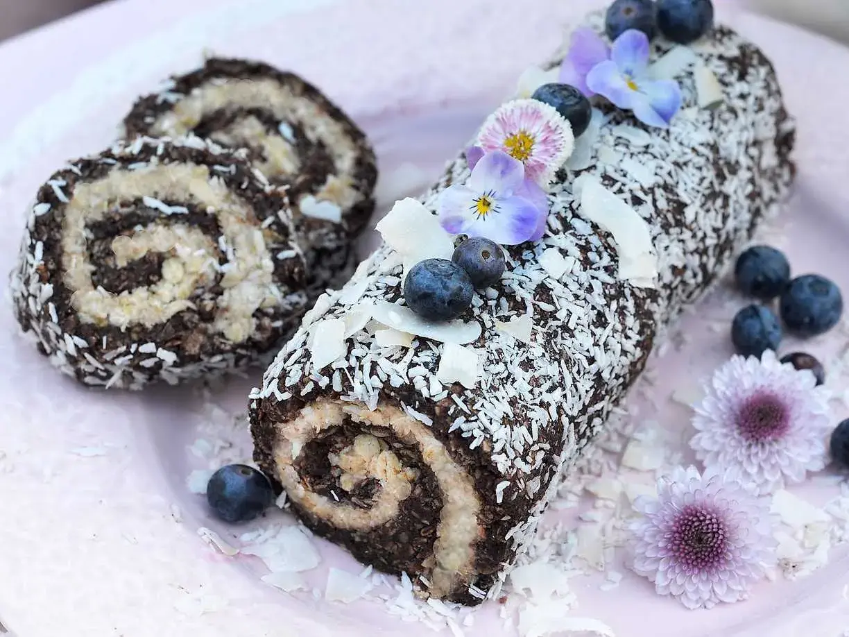 En chokladig rulltårta med kokosflingor, blåbär och blommor. Ett härligt recept på rulltårta från Fredriks fika.