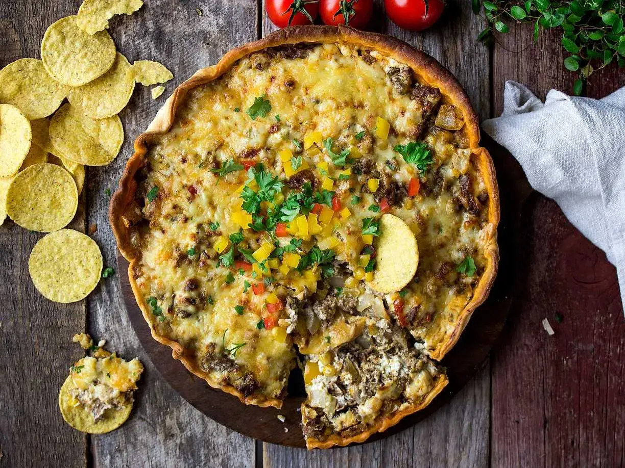 Enkel tacopaj med crème fraiche, toppad med ost, paprika och färsk persilja. Serveras med tortillachips.