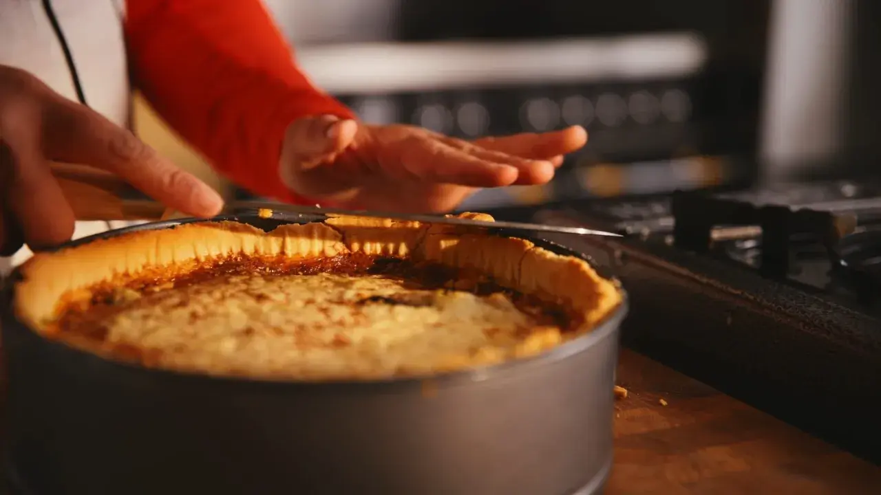 En person skär en gyllene quiche lorraine i en form. Den ser utsökt ut!