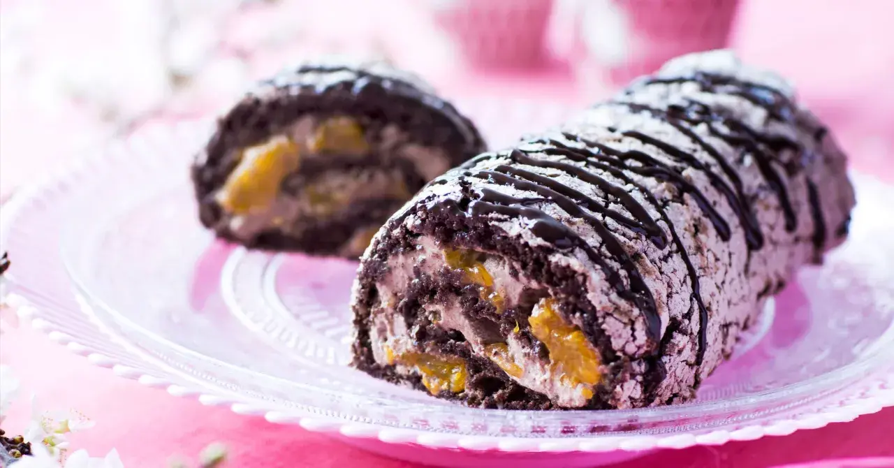 En chokladkaka med aprikosfyllning, perfekt för ett budapestrulle recept. Garnerad med chokladsås och pudersocker.