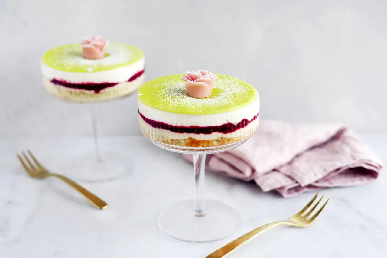 Två vackra prinsesstårtor i glas, dekorerade med en rosa marsipanros och pudrade med florsocker. Perfekt för en festlig fika.