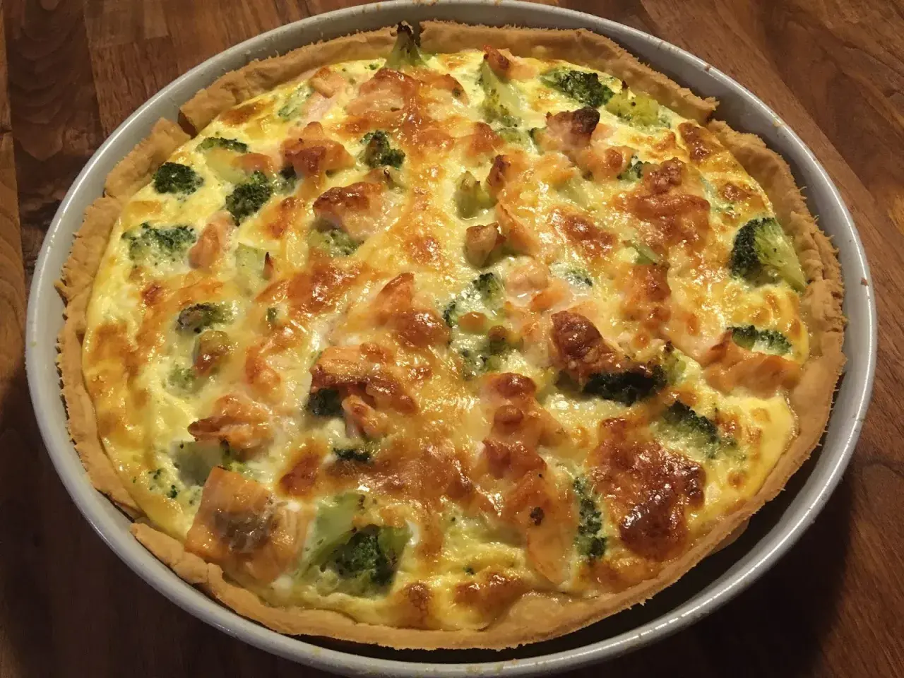 En gyllene laxpaj med broccoli och smält ost, redo att serveras.