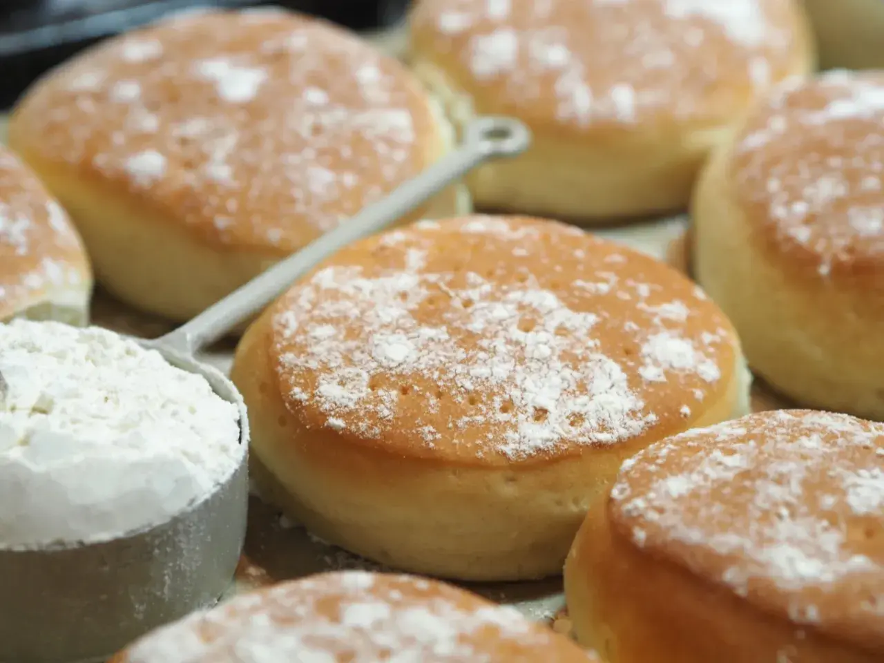 Nybakade tekakor, pudrade med mjöl, redo för ett enkelt tekakor recept. En skopa mjöl syns i förgrunden.