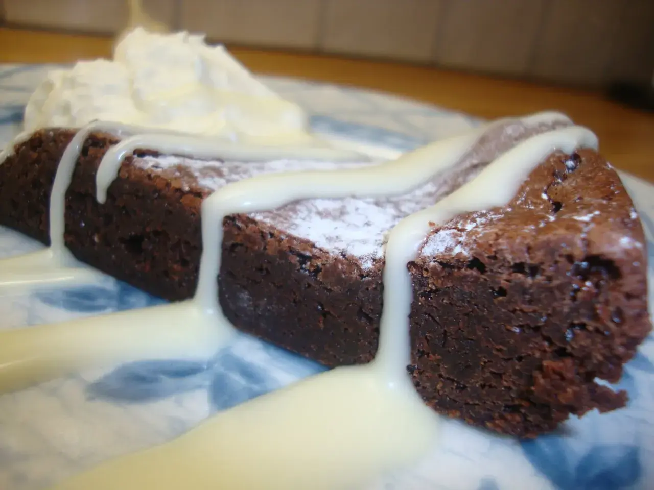 En saftig kladdkaka med sirap, pudrad med florsocker och toppad med vispad grädde.