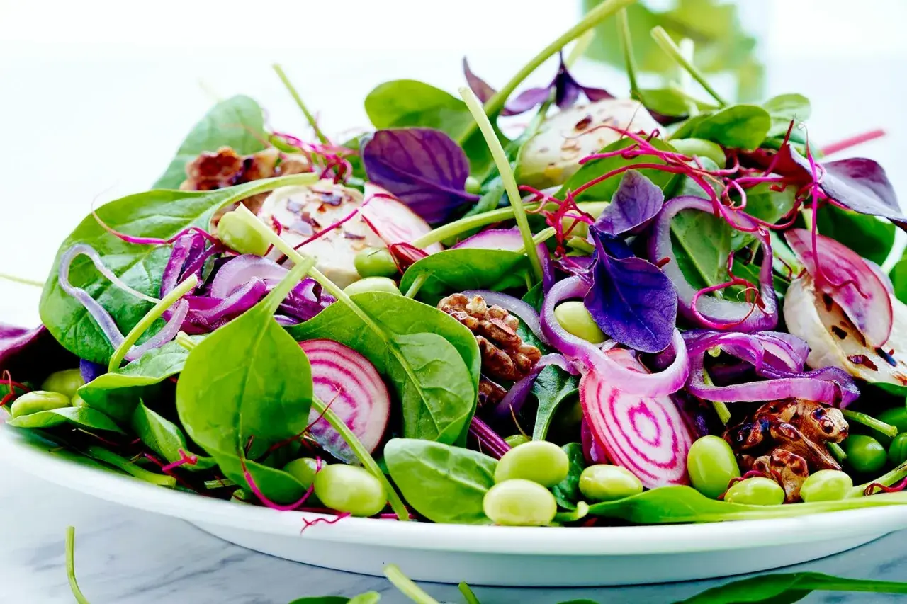 En färgglad sallad med spenat, rödlök, edamamebönor och valnötter. Perfekt som en lätt lunch, och ja, man kan värma spenat till den!