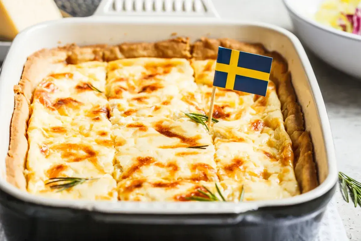 En gyllene västerbottenpaj till många, dekorerad med en svensk flagga och rosmarin. Perfekt för firande!