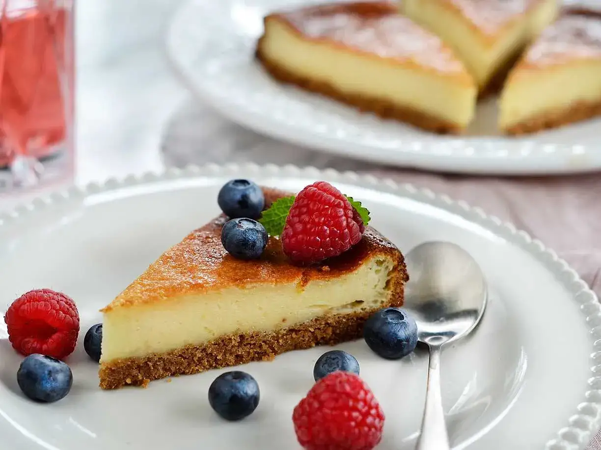 En krämig cheesecake-slice med bär och en sked. Ett perfekt cheesecake recept för fikat.
