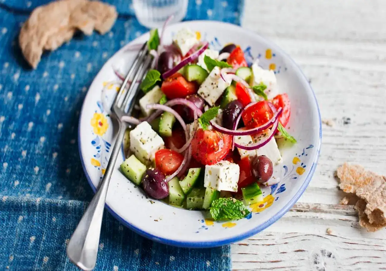 En fräsch grekisk sallad med fetaost, tomater, gurka, rödlök och oliver, garnerad med mynta.