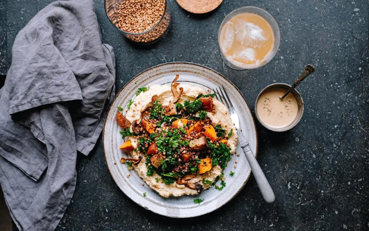 En tallrik med krämig hummus, rostade grönsaker, krispig grönkål och bovete. Ett perfekt exempel på inspirerande vegetariska recept.