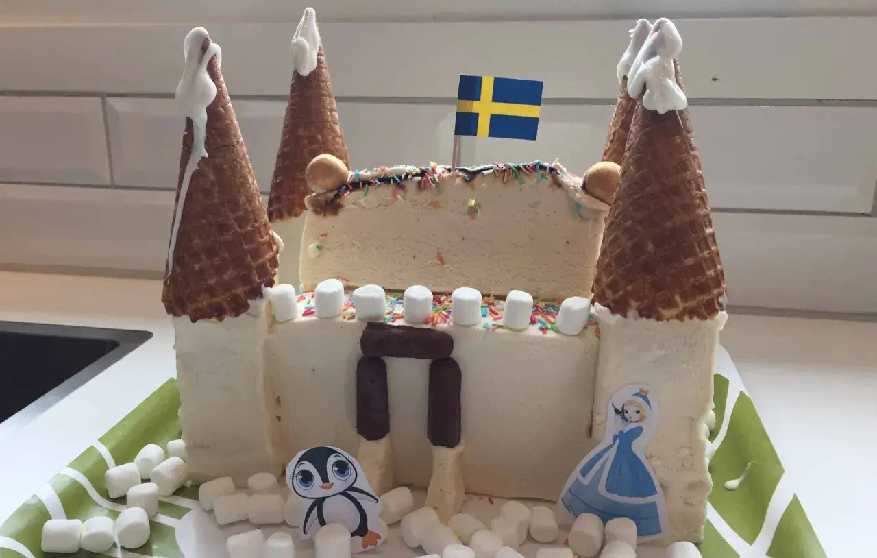 En fantasifull glasstårta formad som ett slott, perfekt för barnkalas. Med svenska flaggan, marshmallows och söta figurer.