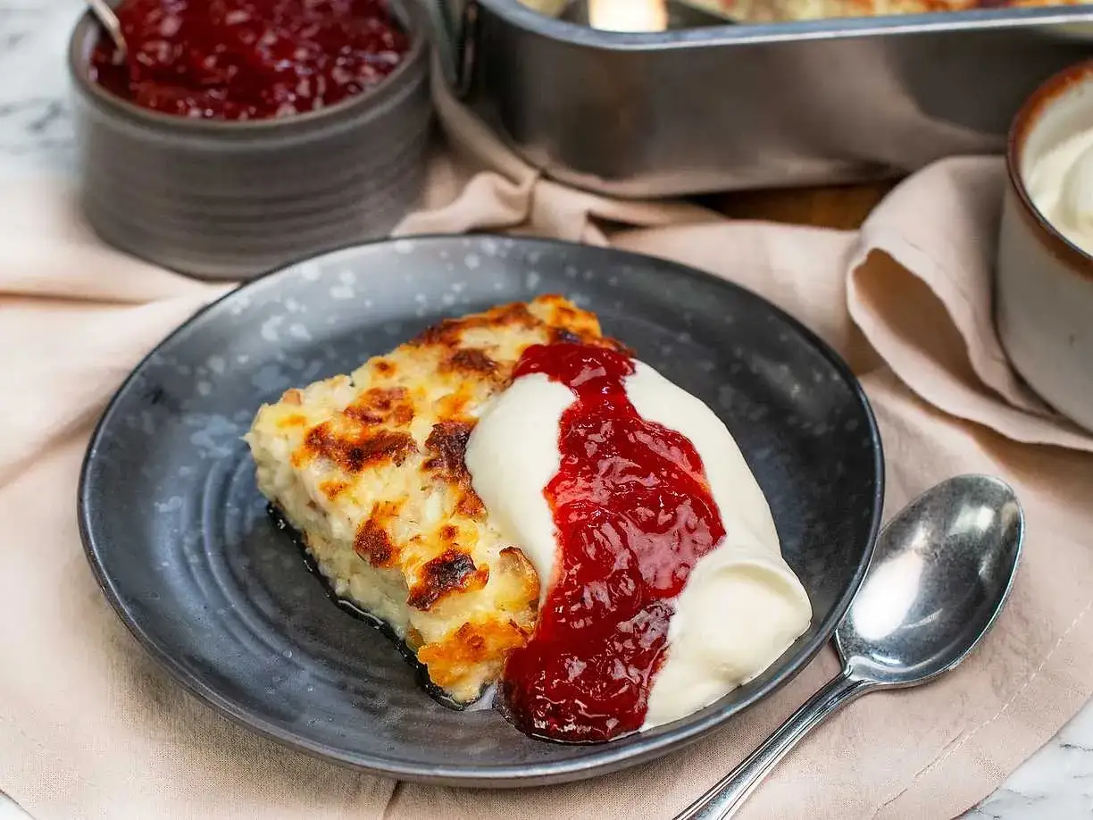 En bit gyllene ostkaka med vispad grädde och rårörda lingon. Ett perfekt ostkaka recept för hembakning.