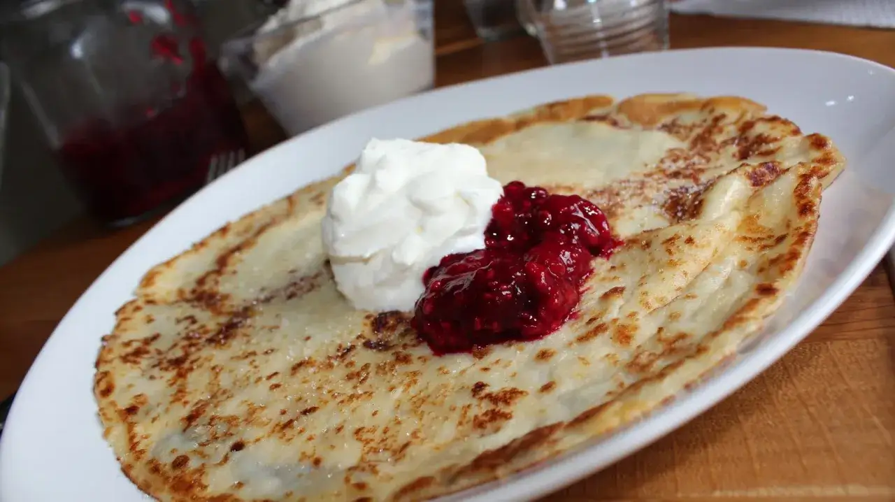 En perfekt pannkaka med vispad grädde och hallonsylt. Ett enkelt pannkakor recept för en mysig fika.