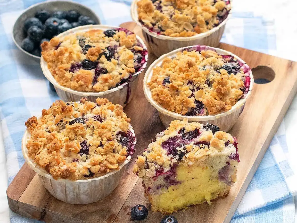 Saftiga muffins med blåbär och smuldeg. En bit visar den fluffiga insidan full av bär.