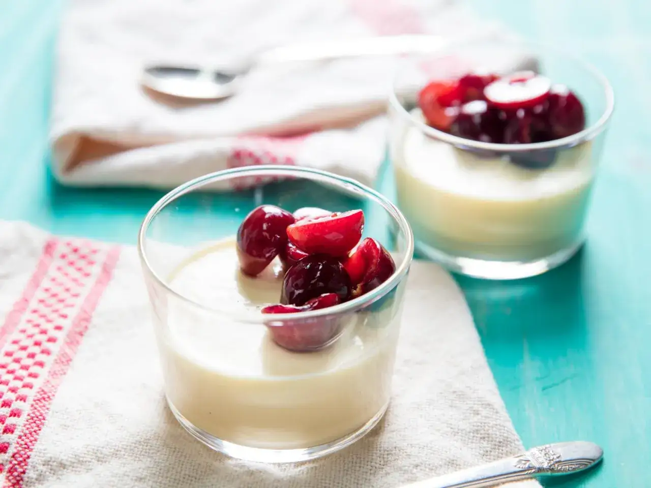 Två glas med krämig panna cotta toppad med körsbär. En härlig dessert som passar perfekt till fikat.