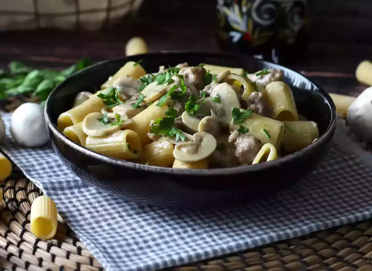 En skål med rig pasta med champinjoner och köttfärssås, toppad med färsk persilja. Ett perfekt champinjoner recept för en mysig middag.