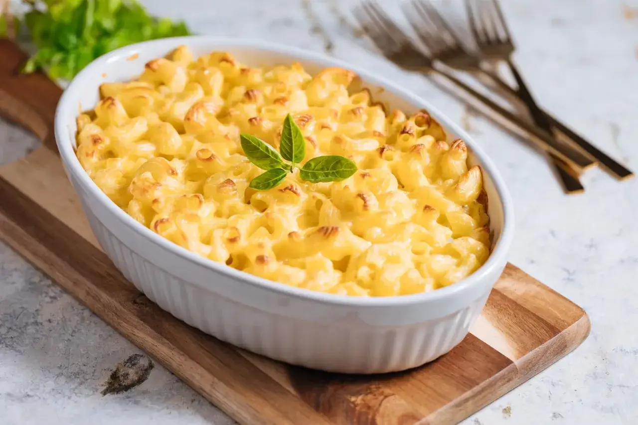 En krämig och gyllene mac and cheese i en vit ugnsform, toppad med färska örter. Perfekt för en mysig middag.