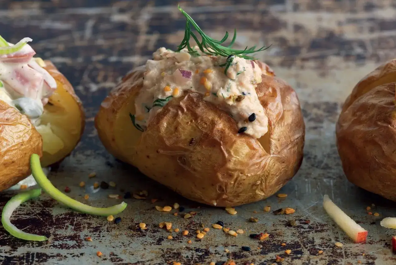 Bakad potatis med en krämig fyllning av lax och dill, toppad med färska örter. En läcker och mättande rätt.