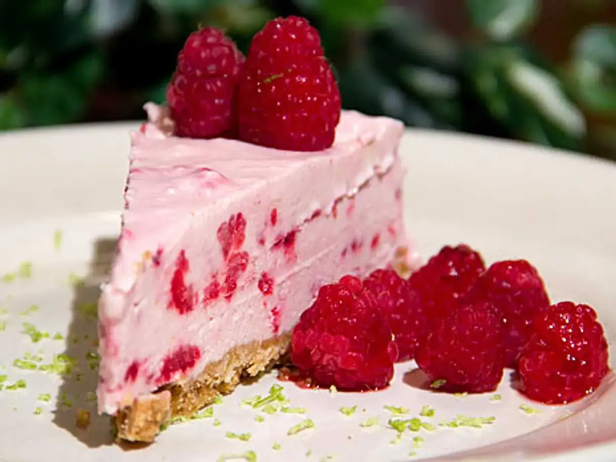 En bit krämig, fryst cheesecake med hallon och färska hallon som dekoration.
