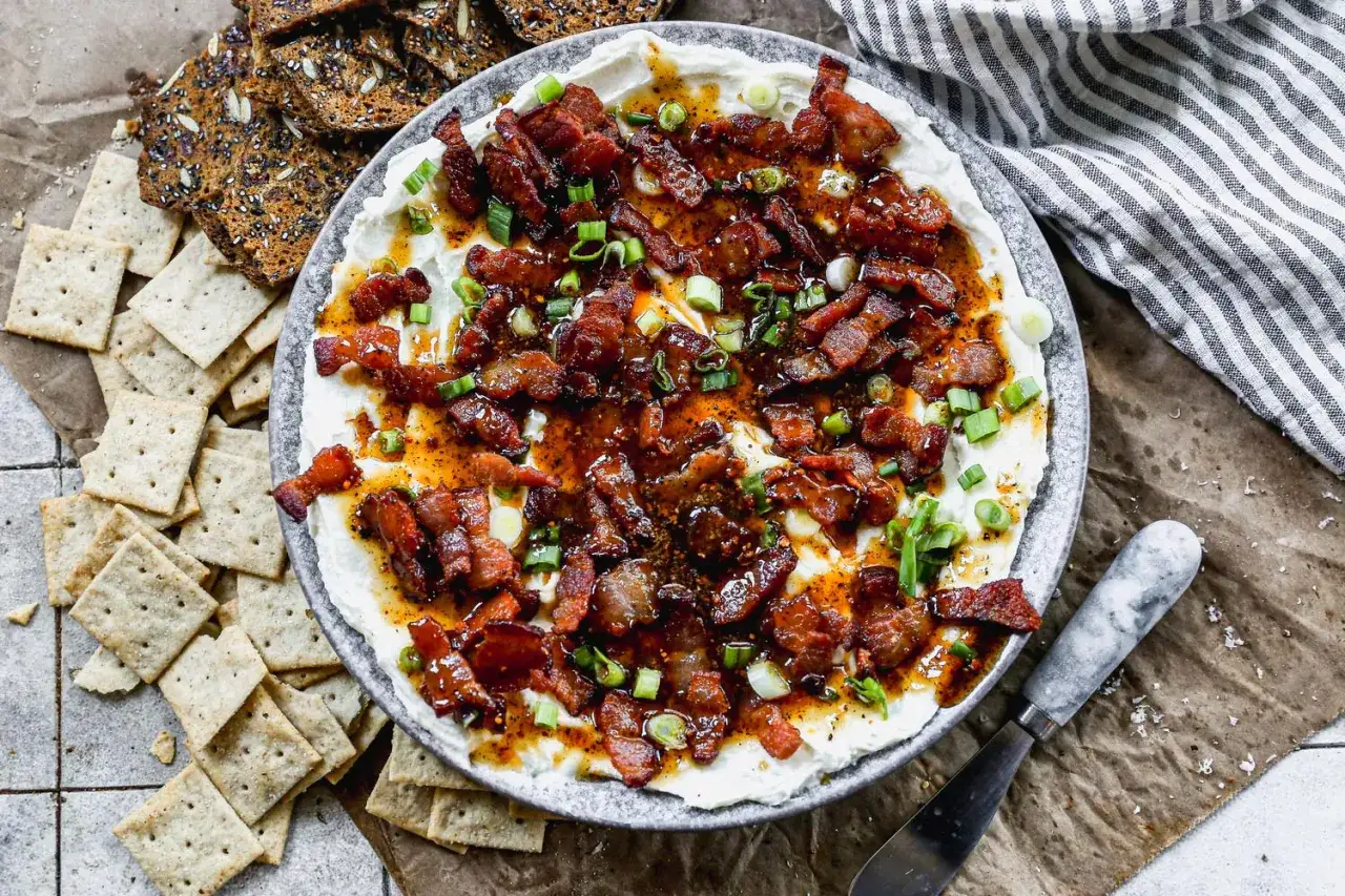Krämig paj med brieost och knaprigt bacon, toppad med salladslök. Serveras med kex.