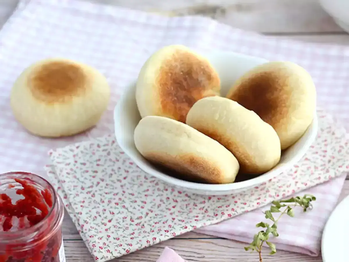 Färska, gyllene english muffins i en skål, redo att avnjutas med sylt.