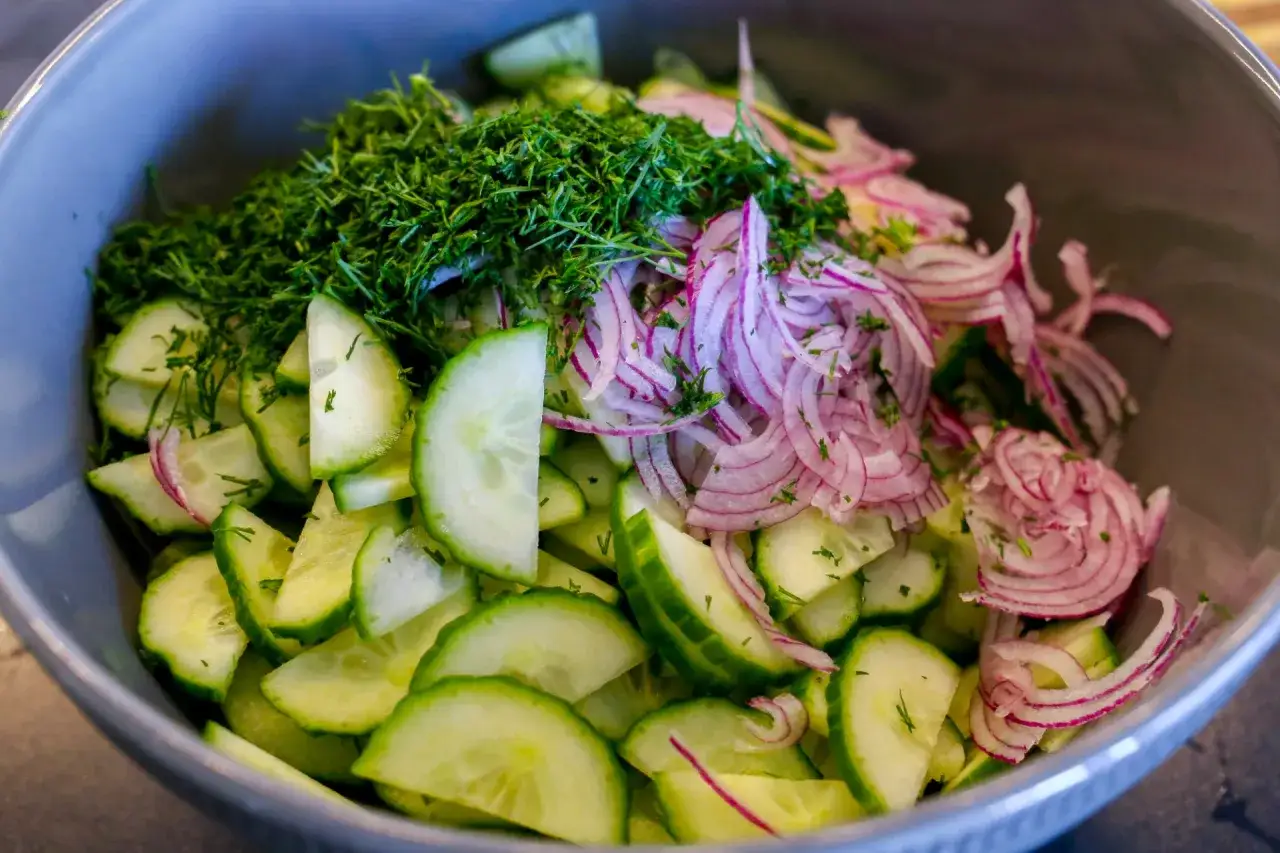 En skål med fräsch gurksallad, perfekt för ett enkelt gurksallad recept. Med skivad gurka, rödlök och dill.